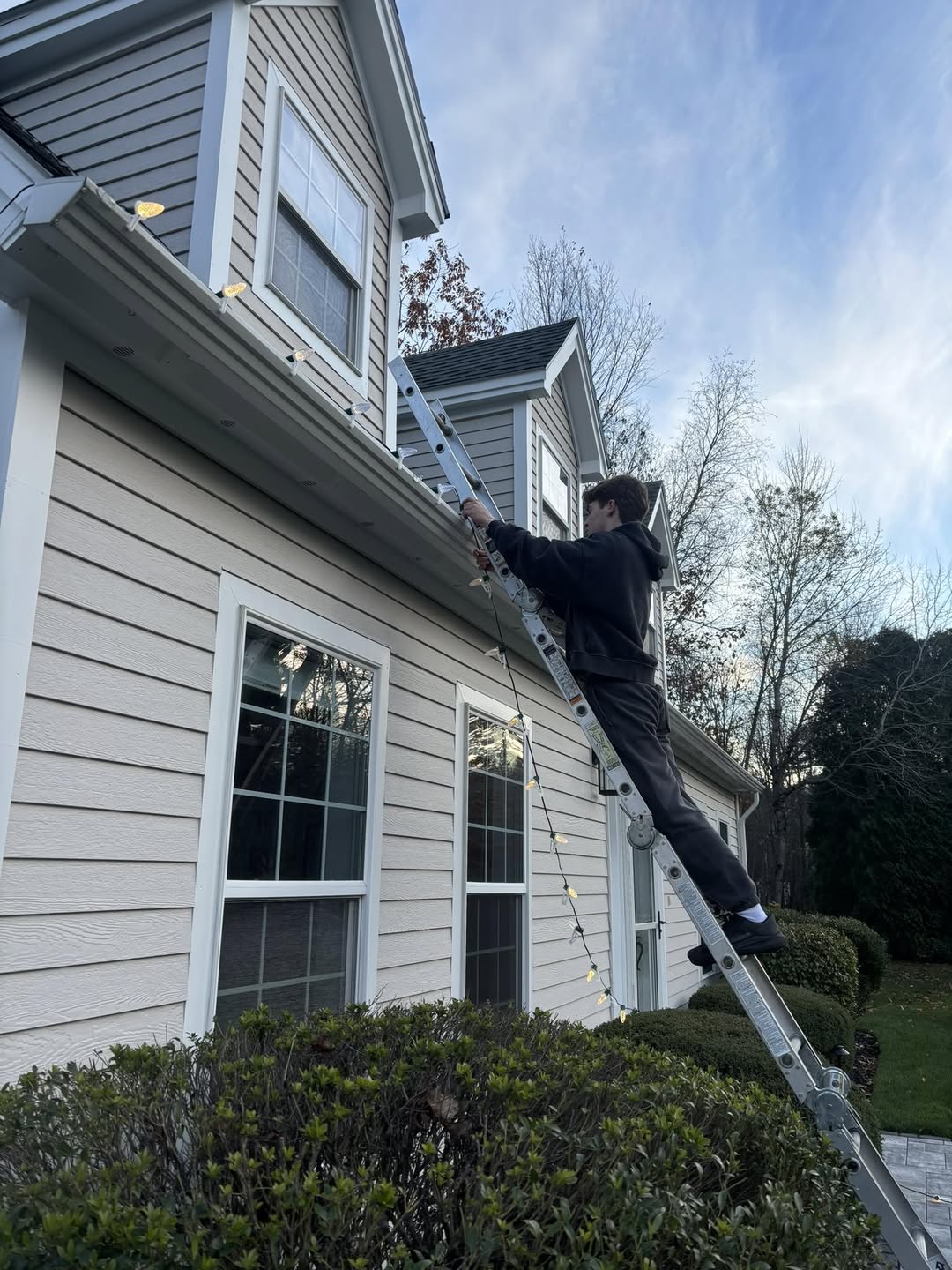 Installer clipping commercial C9 bulbs along a home's gutter line