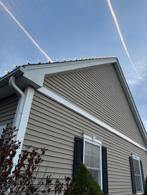 Close-up of C9 bulbs installed along a white roof peak against a blue sky