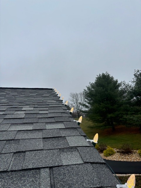 Close view down an illuminated shingle roofline lined with C9 bulbs at night