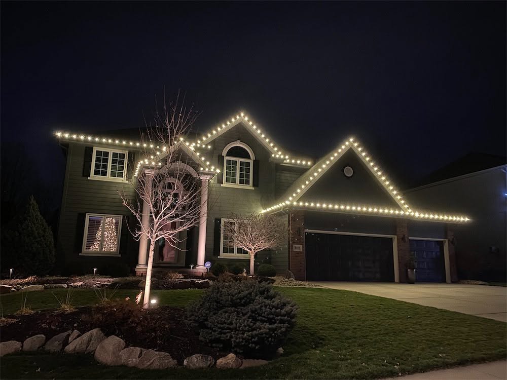 Two-story home with straight C9 roofline lighting and lit landscaping